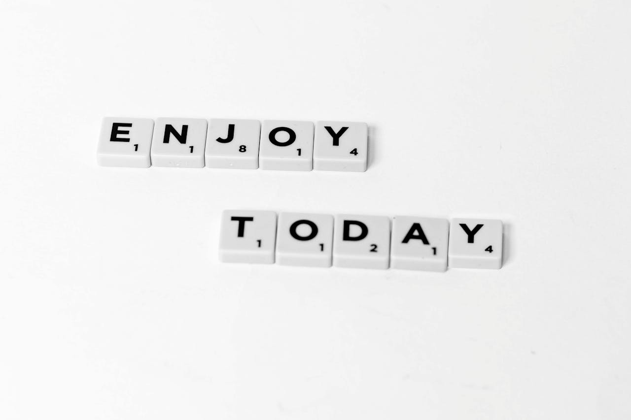 Close-up of letter tiles spelling 'Enjoy Today' on a white background, conveying positivity.